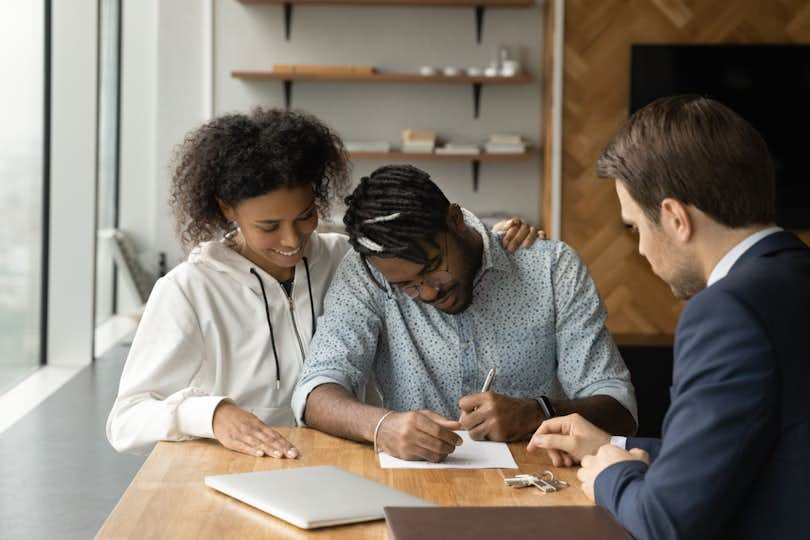 a couple smiles as they complete paperwork for their first home loan