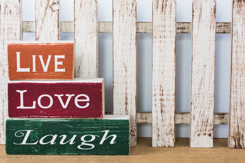 Live love laugh on wooden blocks against a fence.