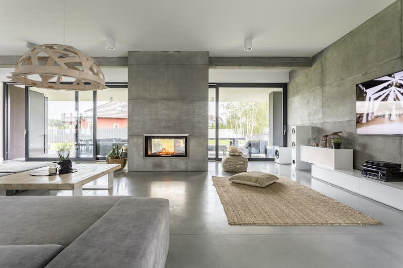 Spacious villa interior with cement wall effect, fireplace and minimal furnishings