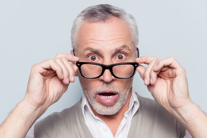 Man looks surprised as he pulls down his glasses