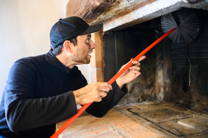Chimney sweep at work in fireplace