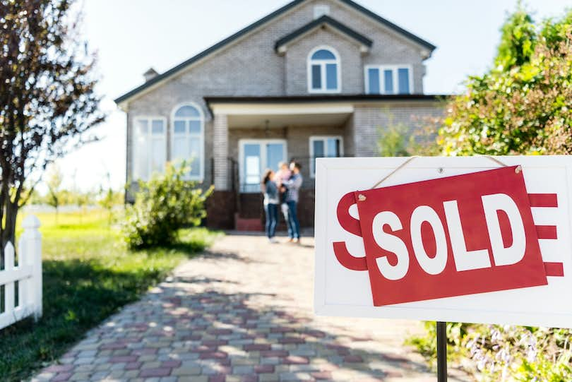 House with sold sign out front and family in background. Sell my house!