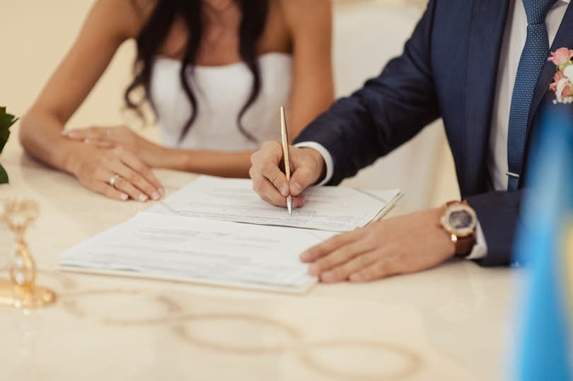 two people in suit and gown signing marriage certificate marriage survey marriage decline partner vs spouse