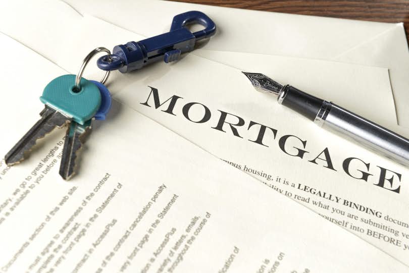 Mortgage note on table with house keys and pen.