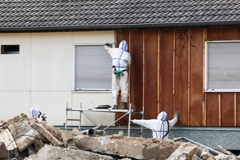 Workers in hazmat suits removed asbestos siding