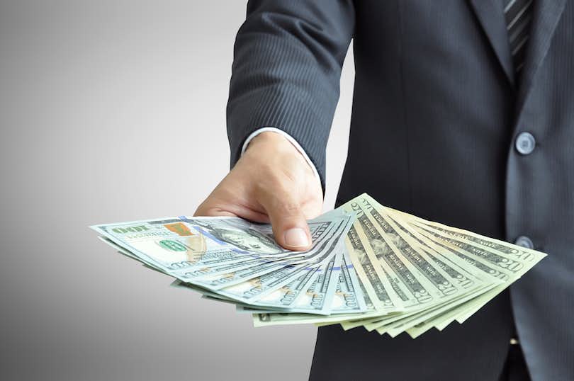 Man in suit holds out money