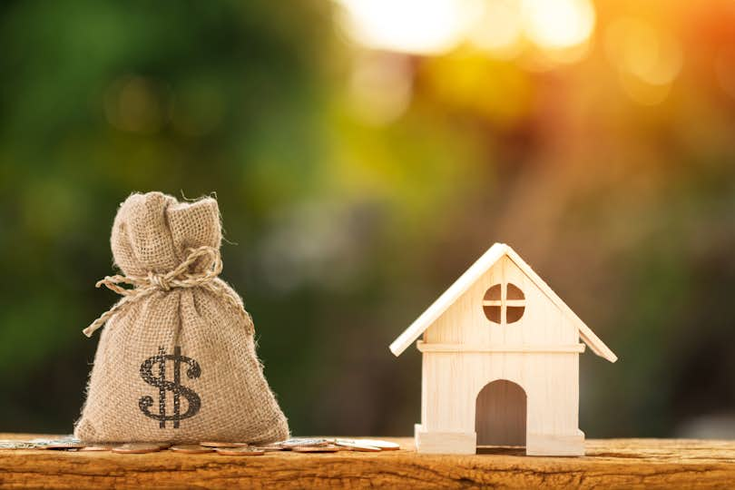 Money bag beside model of house