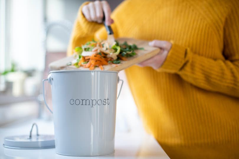 Close Up Of Woman Making Compost From Vegetable Leftovers In Kitchen