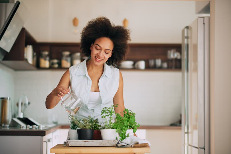 woman gardening fresh herbs at her kitchen